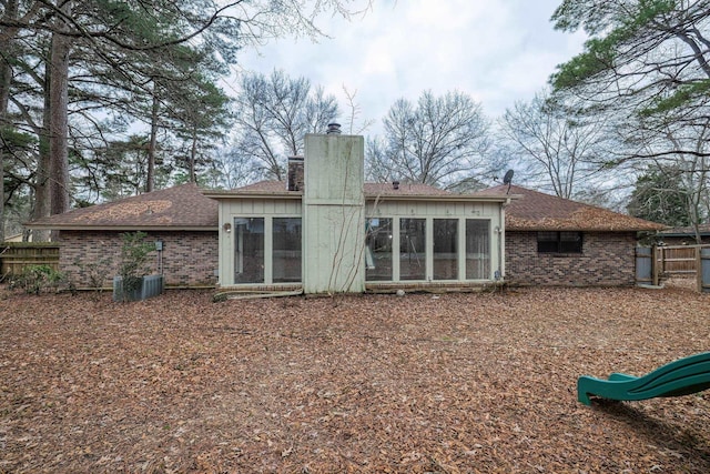 back of property with a playground and a sunroom