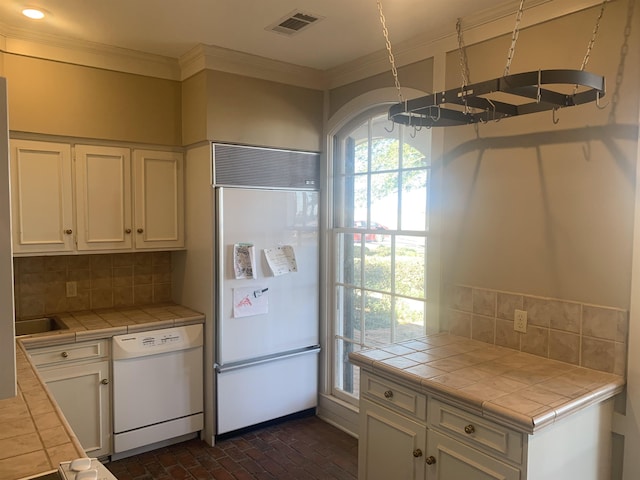 kitchen with tasteful backsplash, tile countertops, dishwasher, paneled fridge, and white cabinets