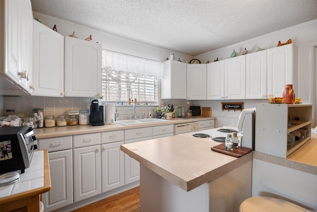 kitchen featuring tasteful backsplash, sink, a textured ceiling, and white cabinets