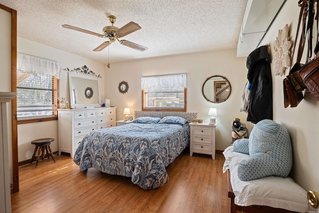 bedroom with ceiling fan, a textured ceiling, and light hardwood / wood-style flooring