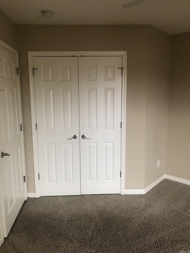 unfurnished bedroom featuring dark carpet and a closet