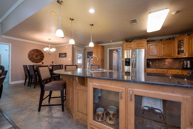 kitchen with pendant lighting, sink, backsplash, a kitchen breakfast bar, and stainless steel refrigerator with ice dispenser