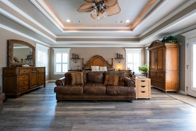 bedroom with a raised ceiling, hardwood / wood-style floors, and multiple windows