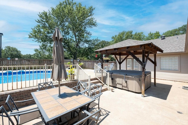 view of patio with a swimming pool with hot tub and a gazebo