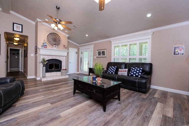 living room with crown molding, a fireplace, hardwood / wood-style flooring, and vaulted ceiling