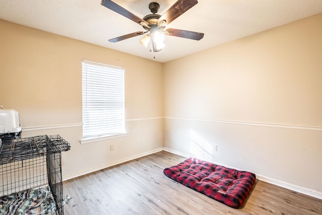 misc room with ceiling fan, light hardwood / wood-style flooring, and a textured ceiling