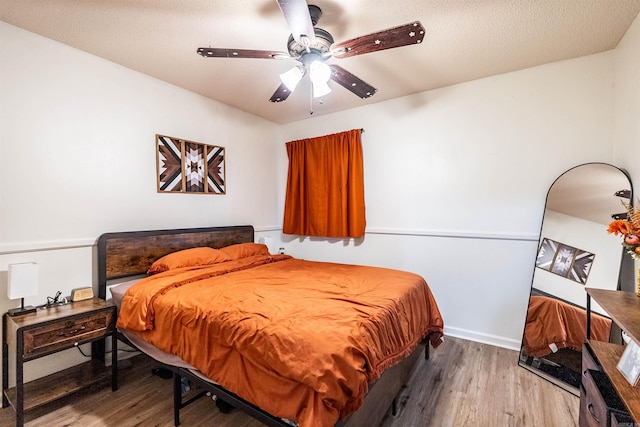 bedroom with hardwood / wood-style flooring, a textured ceiling, and ceiling fan