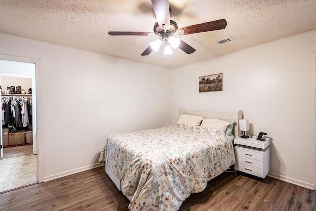 bedroom with dark wood-type flooring, ceiling fan, a closet, and a textured ceiling