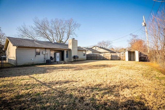 back of property with a shed, central AC unit, and a lawn