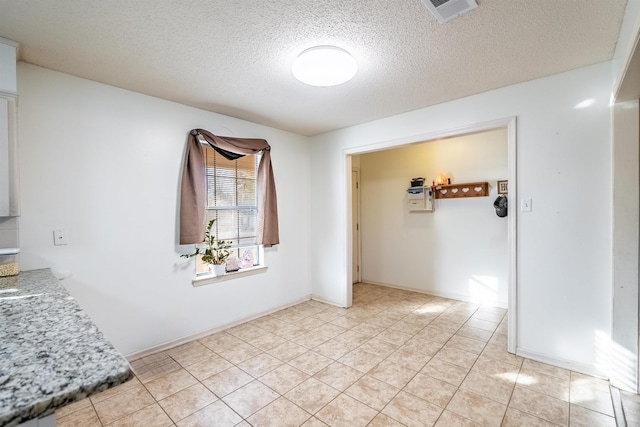 unfurnished room featuring a textured ceiling and light tile patterned floors