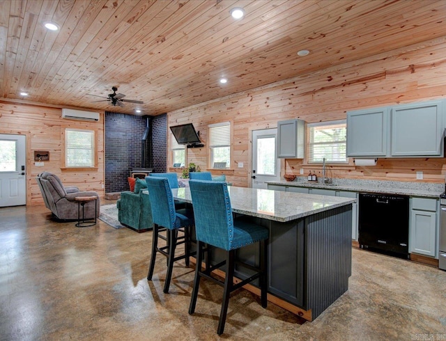 kitchen featuring dishwasher, light stone counters, a kitchen island, an AC wall unit, and a wood stove