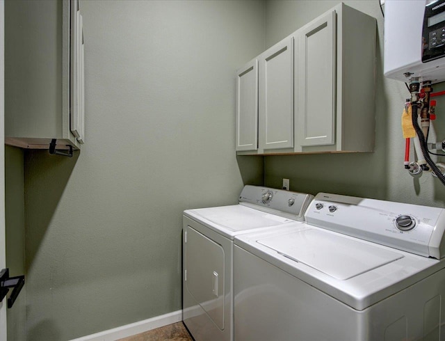 laundry area with cabinets, washer and dryer, and water heater