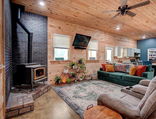 living room with wood ceiling, a healthy amount of sunlight, concrete flooring, and a wood stove