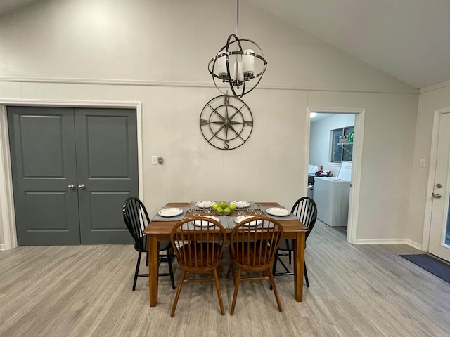 dining room with lofted ceiling, washer / dryer, light hardwood / wood-style floors, and a notable chandelier