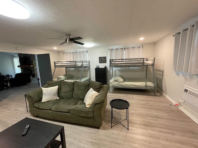 bedroom featuring ceiling fan, a stone fireplace, and light wood-type flooring