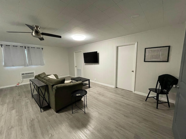 living room with ceiling fan, a wall unit AC, and light hardwood / wood-style flooring