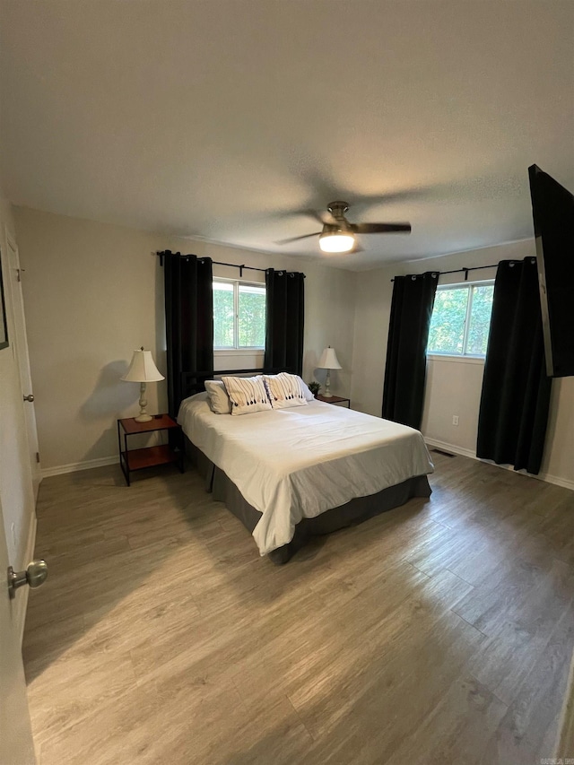 bedroom with multiple windows, ceiling fan, and light hardwood / wood-style floors