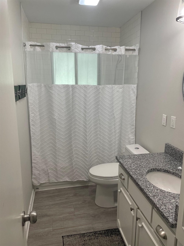 bathroom with hardwood / wood-style flooring, vanity, walk in shower, and toilet