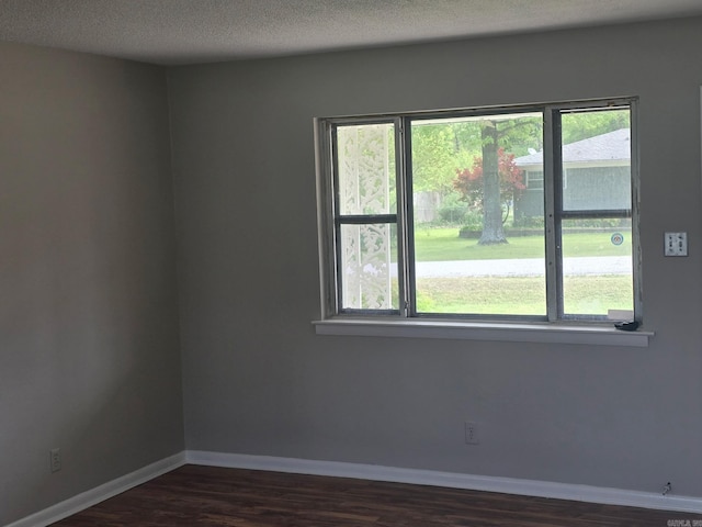 empty room with baseboards, a textured ceiling, and dark wood-style floors