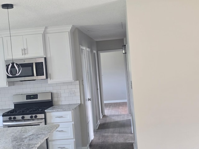 kitchen featuring baseboards, stainless steel appliances, white cabinets, and tasteful backsplash