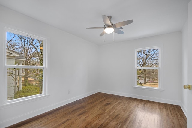 empty room with ceiling fan, plenty of natural light, and dark hardwood / wood-style floors