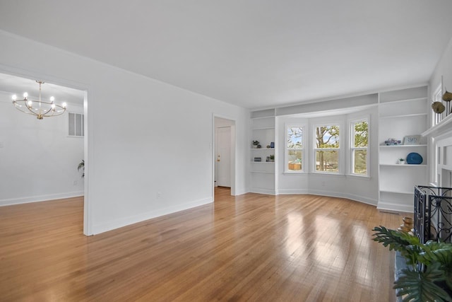 unfurnished living room featuring light hardwood / wood-style floors, built in features, and a notable chandelier