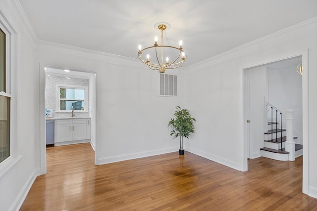 unfurnished dining area featuring crown molding, sink, a notable chandelier, and light wood-type flooring