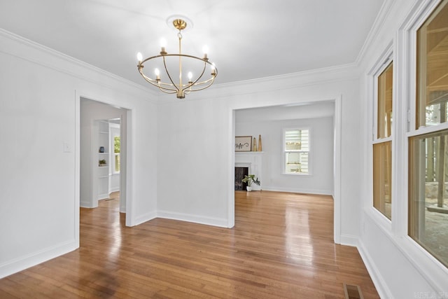 unfurnished dining area featuring ornamental molding, a chandelier, and light wood-type flooring