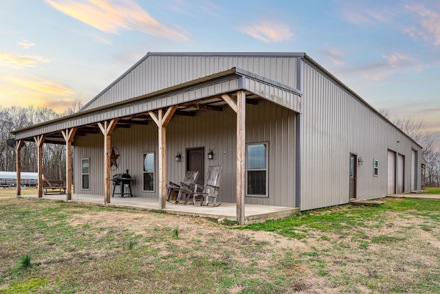 back house at dusk with a garage, a yard, and a patio area