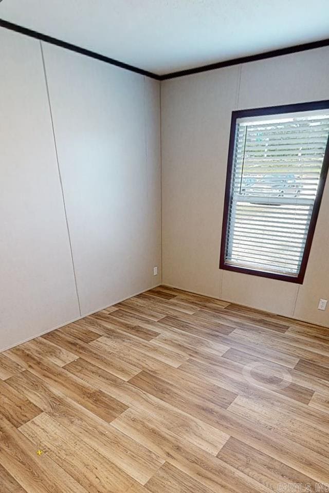 unfurnished room with light wood-style floors and crown molding