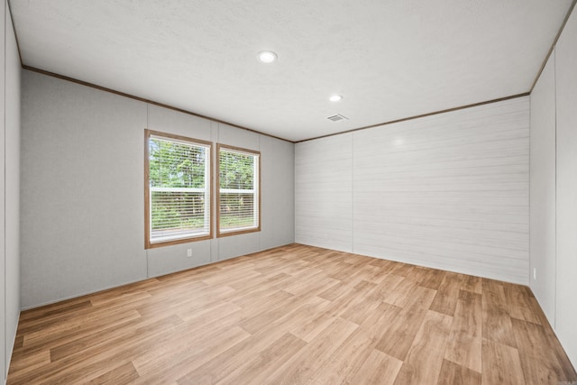 spare room with light wood finished floors, recessed lighting, and crown molding
