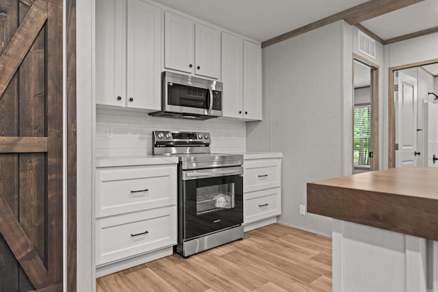 kitchen featuring stainless steel appliances, light wood-style floors, white cabinetry, ornamental molding, and light countertops