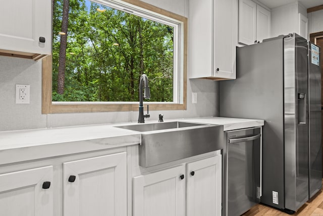 kitchen featuring a sink, stainless steel appliances, healthy amount of natural light, and white cabinetry