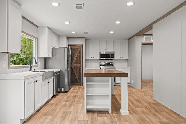 kitchen with appliances with stainless steel finishes, butcher block counters, open shelves, backsplash, and light wood-type flooring