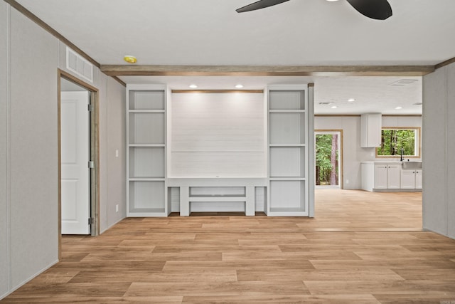 unfurnished living room with ceiling fan, light wood finished floors, and a sink