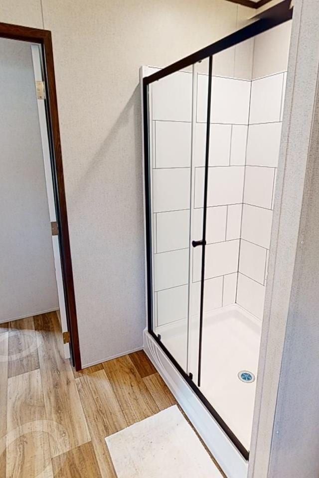 bathroom with wood finished floors and a stall shower