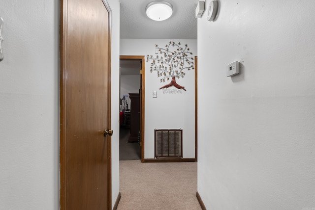 corridor featuring light carpet and a textured ceiling