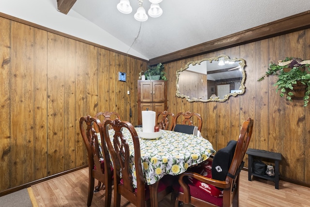 dining area with wooden walls, lofted ceiling with beams, and light wood-type flooring