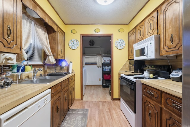 kitchen with sink, tasteful backsplash, a textured ceiling, light wood-type flooring, and white appliances