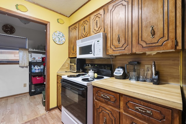 kitchen with a textured ceiling, electric range, and light hardwood / wood-style floors