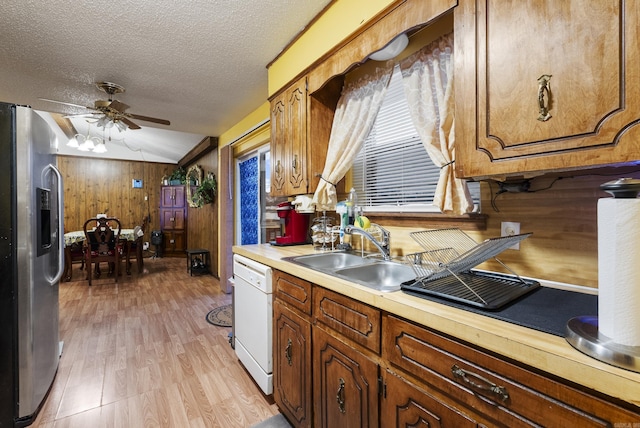 kitchen featuring vaulted ceiling, dishwasher, sink, stainless steel fridge, and a textured ceiling