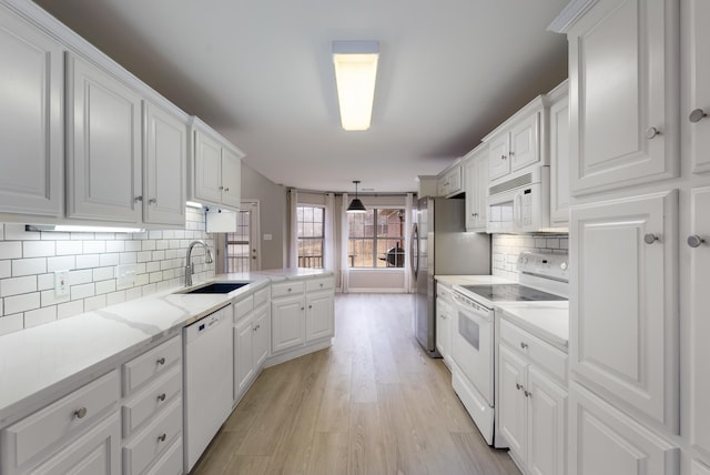 kitchen with sink, white cabinetry, decorative light fixtures, light wood-type flooring, and white appliances