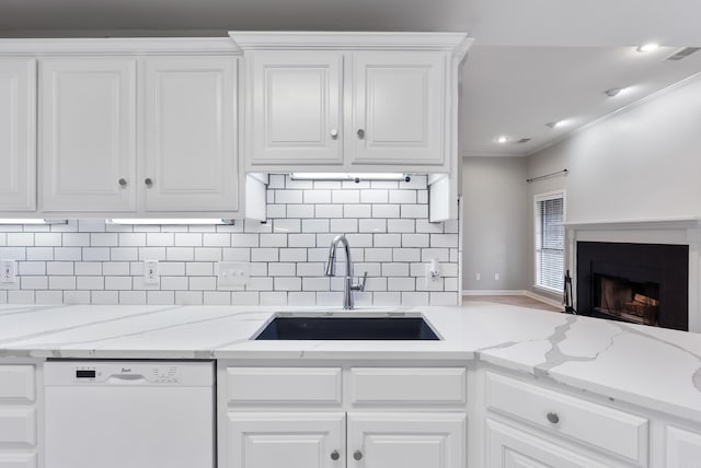 kitchen with sink, white cabinetry, light stone counters, ornamental molding, and white dishwasher