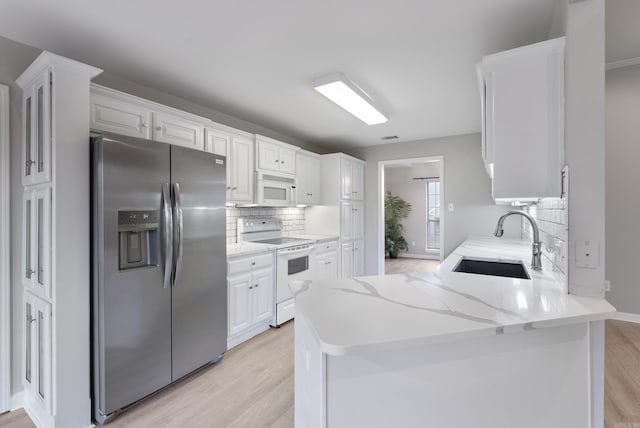 kitchen with white cabinetry, white appliances, kitchen peninsula, and sink