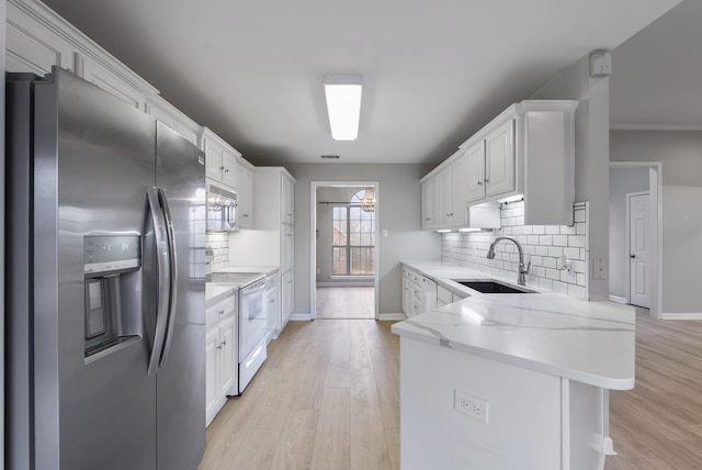 kitchen with white cabinetry, sink, white appliances, and kitchen peninsula