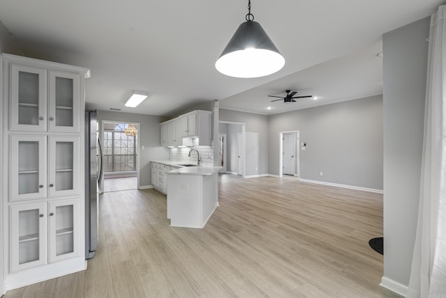 kitchen with pendant lighting, tasteful backsplash, sink, white cabinets, and light hardwood / wood-style flooring