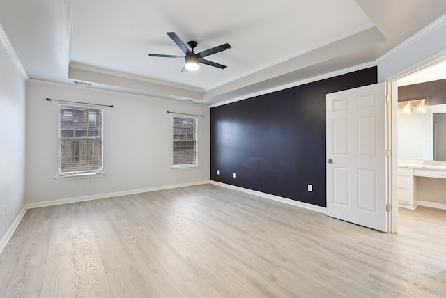 unfurnished room with a raised ceiling, crown molding, ceiling fan, and light hardwood / wood-style flooring