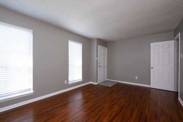 empty room featuring dark hardwood / wood-style floors and a textured ceiling