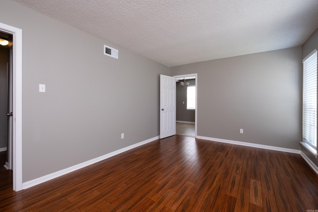 unfurnished room featuring a wealth of natural light, dark hardwood / wood-style floors, and a textured ceiling