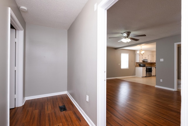 corridor featuring dark hardwood / wood-style flooring, a textured ceiling, and a chandelier